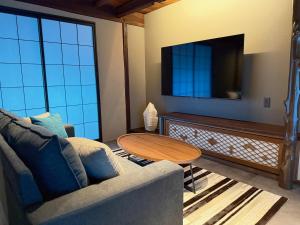 un soggiorno con un divano, un tavolo e una TV di SORAIRO Miyajima a Hatsukaichi