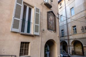 萨卢佐Casa Piazzetta is waiting for you!的街道旁有一栋装有白色百叶窗的建筑