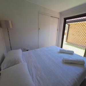 Un dormitorio con una cama blanca con dos toallas encima. en Relaxation room on super cool side of house, en Gold Coast