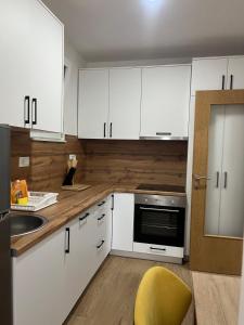 a kitchen with white cabinets and a yellow chair at Apartment Lara in Mostar