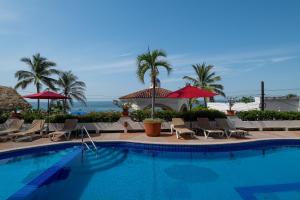 a swimming pool with chairs and umbrellas and the ocean at 2BR Oceanside Resort Condo Pool & Private Beach in Puerto Vallarta