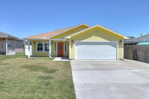 a yellow house with a white garage at A Wave From It All in Rockport