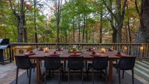 une table en bois sur une terrasse avec des chaises dans l'établissement Lodge-Style Home Near Gatlinburg w Theater Hot Tub Game Room Evergreen Escape by AvantStay, à Pittman Center