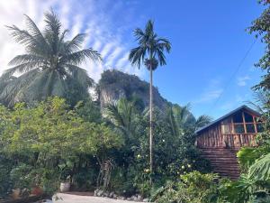 a palm tree in front of a house with a mountain at Wood Haven Homestay in Ninh Binh