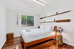 a bedroom with a bed with white sheets and a window at Nonna and Pops in Mylestom