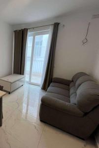 un sofá en una sala de estar con una gran ventana en Qawra Seaside Birch Leaf, en St Paul's Bay