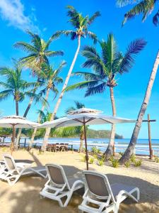 een groep stoelen en parasols op een strand bij The Sanctuary in El Nido