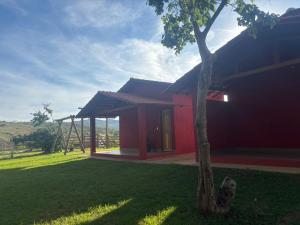 a red house with a tree in front of it at Tríade Chalé da Canastra 2 in São Roque de Minas