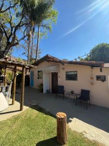 a house with two chairs and a table in the yard at Chalé Aconchegante Com Piscina e Ótima Localização in Serra Negra