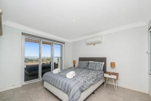 a bedroom with a bed and a large window at Oceans Waves - Luxury Apartment with ocean views in Lancelin