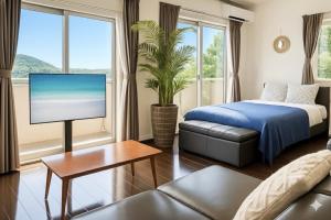 une chambre avec un lit, une télévision et un canapé dans l'établissement オーシャンテラス瀬底303, à Ufugumui