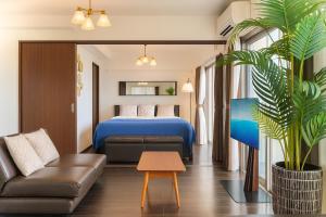 une chambre d'hôtel avec un lit, un canapé et une plante dans l'établissement オーシャンテラス瀬底303, à Ufugumui
