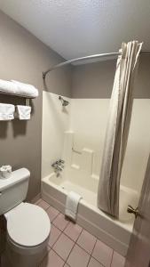 a bathroom with a toilet and a tub and a sink at Colonial Inn in Shawnee +33 photos
