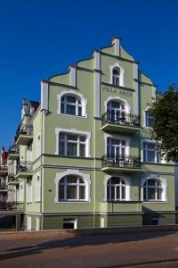 un edificio verde con ventanas y balcones blancos en Apartamenty Villa Artis en Świnoujście