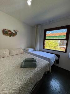 a bedroom with two beds and a window at Le Corsaire in Búzios +22 photos