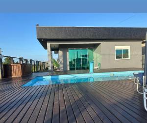 a house with a wooden deck with a swimming pool at Casa com Piscina in Arroio do Sal