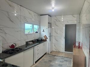 a kitchen with white marble walls and a window at Casa com Piscina in Arroio do Sal