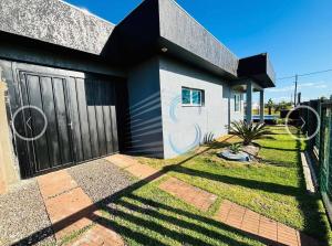 a house with a black door and a fence at Casa com Piscina in Arroio do Sal
