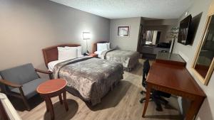 a hotel room with two beds and a desk at Colonial Inn in Shawnee