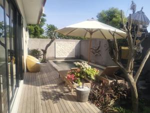 a patio with an umbrella and a bench with flowers at Villa Puri Mesari Amed in Amed
