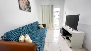 un soggiorno con un divano blu e una TV a schermo piatto di Casa Ampla com Ar Condicionado 450m praia Rua Canoas a Piçarras