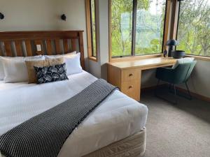 a bedroom with a bed with a desk and a chair at Pukawa Villas Formerly Oreti Village Resort in Kuratau