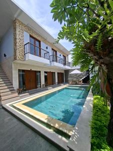 a villa with a swimming pool in front of a house at Mahesa Seminyak in Seminyak