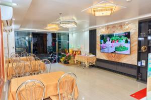 Un restaurante con mesas y sillas y un televisor en la pared. en Ngoc Linh Cat Ba Hotel, en Cat Ba