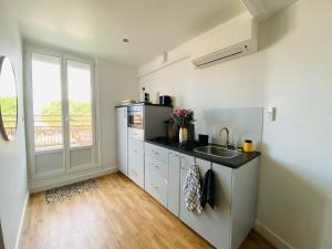 a kitchen with a sink and a refrigerator at Cocon Romantique & Bain Nordique sur Vue Panoramique à Vichy in Vichy