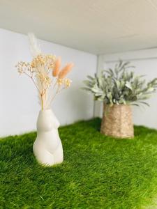 a white vase with flowers sitting on the grass at Cocon Romantique & Bain Nordique sur Vue Panoramique à Vichy in Vichy +4 photos