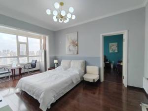 ハルビン市にあるCentral Street River View Apartmentの白いベッドルーム(大型ベッド1台、椅子付)