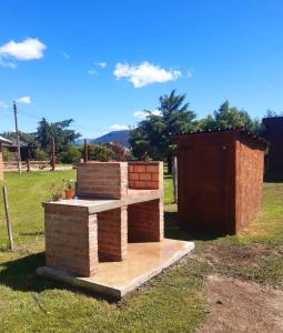 a brick barbecue grill in a field of grass at Cabañas Alma del Sur in El Hoyo