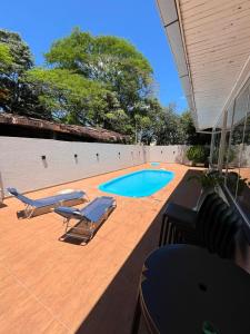 um pátio com cadeiras e uma piscina em Casa Aconchego Fóz em Foz do Iguaçu