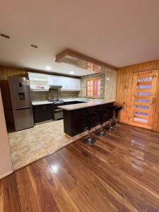 a large kitchen with a counter and bar stools at Alojamiento casa in Temuco