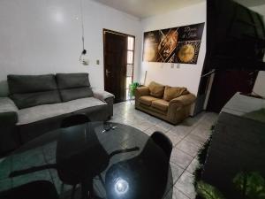 a living room with a couch and a glass table at POUSADA TEMPORADA BIBi casa inteira com café in São Gabriel