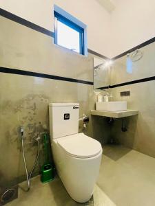 a bathroom with a white toilet and a sink at Tropictide Weligama in Weligama
