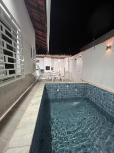 Una gran piscina con azulejos azules en una habitación. en Casa Aconchegante em Itanhaem- Piscina e Churrasqueira 10 pessoas, en Itanhaém