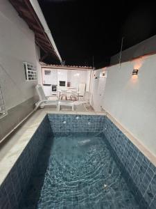 una piscina de agua con sillas y una mesa en Casa Aconchegante em Itanhaem- Piscina e Churrasqueira 10 pessoas, en Itanhaém