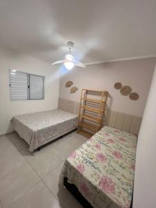 Un dormitorio con dos camas y un ventilador de techo. en Casa Aconchegante em Itanhaem- Piscina e Churrasqueira 10 pessoas, en Itanhaém