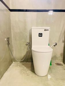 Un inodoro blanco en un baño con una manguera. en Tropictide Weligama, en Nikawatawana