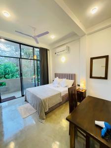 Un dormitorio con una cama y una mesa y una ventana. en Tropictide Weligama, en Nikawatawana