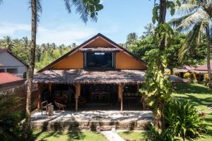 a house with a thatched roof and palm trees at Amy's Place Sumatra in Krui