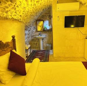 a yellow room with a bed and a sink at Kasr-ı Han Konağı Otel in Mardin