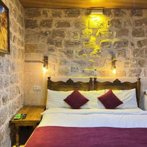 a bed in a room with a stone wall at Kasr-ı Han Konağı Otel in Mardin