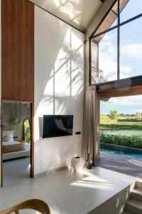 een woonkamer met een groot raam en een televisie bij Sava Villa Ubud Rice Fields View in Tegalalang +20 foto's