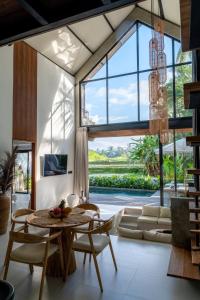 een woonkamer met een tafel en stoelen en een groot raam bij Sava Villa Ubud Rice Fields View in Tegalalang