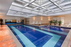 a large swimming pool in a large building at Flat completo no hotel Comfort de Alphaville in Barueri