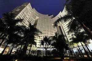 a large building with palm trees in front of it at Flat completo no hotel Comfort de Alphaville in Barueri