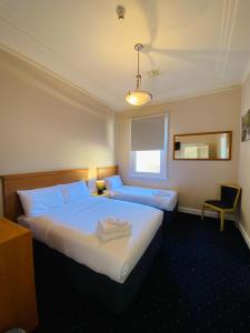 a hotel room with two beds and a mirror at Gardners Inn Hotel in Blackheath