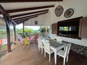 a porch with a table and chairs and a clock at Villa F3, Eden Krys, a cocoon of tranquility in La Trinité